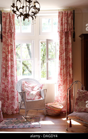 Canne peint chaise face à la fenêtre avec des rideaux de toile de Jouy rose en français pays chambre Banque D'Images