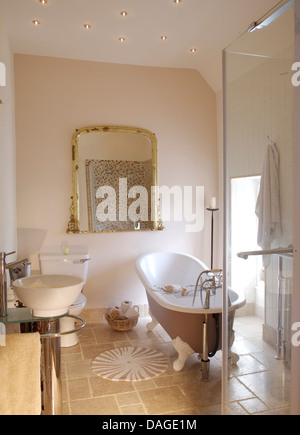 Baignoire et douche en verre de grand cabinet de salle de bains moderne avec grand miroir antique et carrelage en pierre Banque D'Images