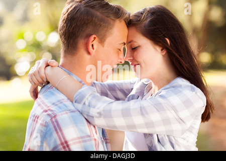 Jeune couple hugging affectueux avec les yeux fermés à l'extérieur Banque D'Images