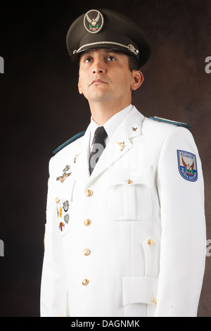 Un officier masculin de la police nationale équatorienne prend une pose formelle, portant un uniforme de robe blanc avec des boutons dorés, une cravate noire et une casquette de service foncée avec un emblème brodé. L'uniforme Banque D'Images