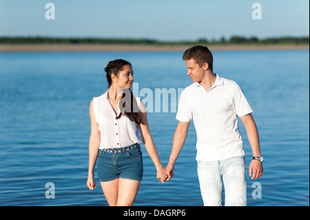 Couple in love les promenades au bord de la rivière en short en jean et une chemise blanche. Banque D'Images