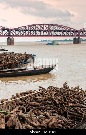 Bateaux chargés de bois de chauffage pour alimenter la crémation ghats le long du Gange à Varanasi avec le Mahatma Gandhi bridge. Banque D'Images