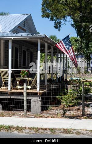 Ancienne gloire American stars and stripes flag waves from large véranda d'un bungalow Cedar Key, Floride. Banque D'Images