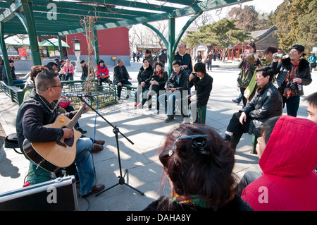 L'écoute du peuple chinois jeune homme jouant de la guitare et chanter dans le parc Beihai, Dongcheng District, Beijing, Chine Banque D'Images