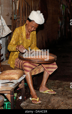 Personnes âgées dame en costume traditionnel balinais, le tri des haricots au marché du matin de Singaraja. Singaraja, Bali, Indonésie Banque D'Images