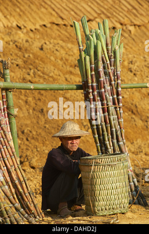 Dans l'homme Hmong noir distinctif vestimentaire et de la canne à sucre à vendre chapeau marché. Pouvez Cau, près de Bac Ha, province de Lao Cai, Vietnam Banque D'Images