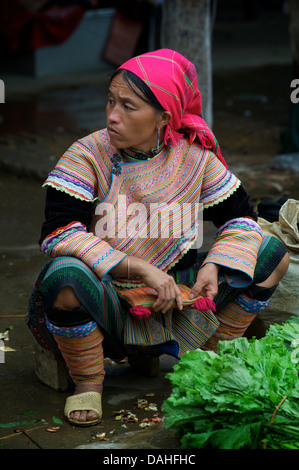 Femme Flower Hmong en costume tribal distinctif vendre des légumes au marché de Bac Ha, province de Lao Cai, Vietnam Banque D'Images