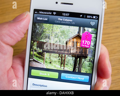 En utilisant Airbnb app de réserver hébergement de vacances de luxe dans une maison de l'arbre avec un smartphone iPhone 5 Banque D'Images