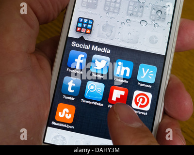 L'utilisation de l'iPhone 5 blanc téléphone intelligent pour accéder à de nombreuses applications de médias sociaux depuis l'écran d'accueil Banque D'Images