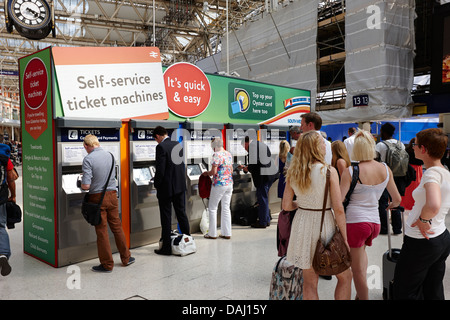 File d'attente des passagers à des distributeurs de billets en libre service à Waterloo hors-sol national rail gare London, England uk Banque D'Images