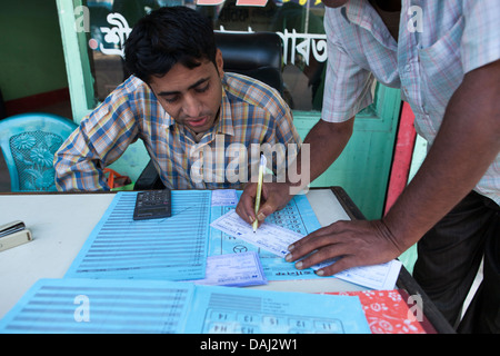 L'écriture et l'émission d'un billet d'autobus à partir de Srimongol à Dhaka à une table en face de la compagnie de bus bureau à Srimongol, Bangladesh Banque D'Images