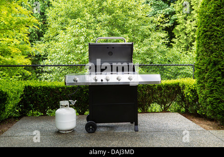 Photo horizontale d'une cuisinière, d'un grand barbecue avec couvercle en place, sur une terrasse extérieure en béton avec fond woods Banque D'Images