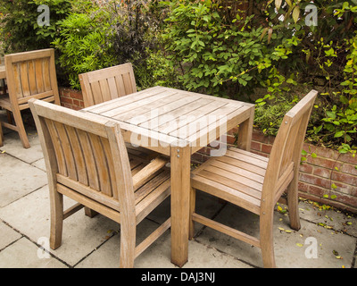 Photo de l'ancien table et chaises en bois en plein air avec barrière en brique et les verts arbres en arrière-plan Banque D'Images
