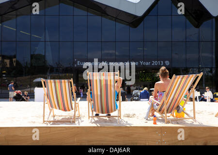 Glasgow, Ecosse, Royaume-Uni. 14 juillet 2013. Les visiteurs prendre le soleil à l'homme urbain fait de sable avec chaises longues à l'extérieur du Riverside Museum à Glasgow Crédit : PictureScotland/Alamy Live News Banque D'Images