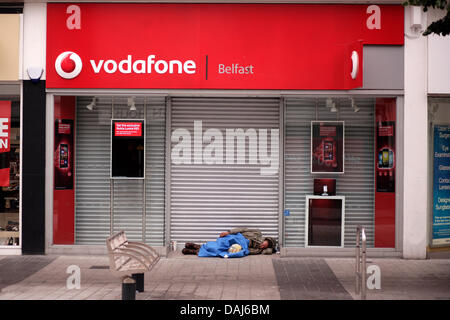 L'Irlande du Nord, Belfast 14 juillet 2013. Un sans-abri se trouve dormant dans l'embrasure de Vodafone dans Belfast City Centre Banque D'Images