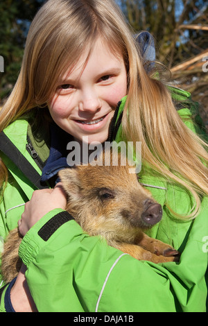 Le sanglier, le porc, le sanglier (Sus scrofa), girl holding a shote sur son bras, Allemagne Banque D'Images