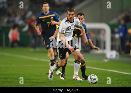 L'Allemagne Lukas Podolski (EDDV) avant de la balle avec l'Austrialia Luke Wilkshire et Brett Emerton (L) au cours de la match amical contre l'Allemagne à la Borussia-Park-Stadium à Moenchengladbach, Allemagne, 29 mars 2011. Photo : Revierfoto Banque D'Images