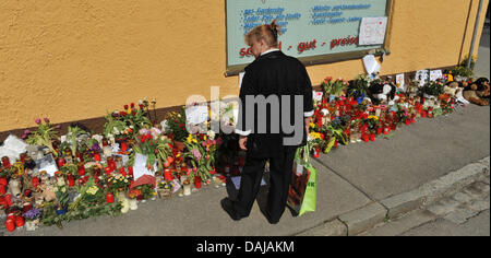 Une femme observe des fleurs, des bougies et des ours en peluche situé en face d'une maison, où deux jeunes filles ont été assassinées le 24 mars 2011 à Krailling, Allemagne, 29 mars 2011. Le service funèbre pour les deux sœurs Chiara (8) et Sharon (11) a lieu dans la soirée du 29 mars 2011. Photo : Andreas Gebert Banque D'Images