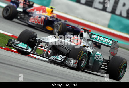 Pilote de Formule 1 allemand Michael Schumacher de Mercedes GP steers sa voiture à travers une courbe dans l'avant du pilote de Formule Un Australien Mark Webber de Red Bull après le début de la Grand Prix de Malaisie le Grand Prix de Formule 1 de la Malaisie à l'extérieur du circuit Sepang, Kuala Lumpur, Malaisie, le 10 avril 2011. Photo : JENS BUETTNER Banque D'Images