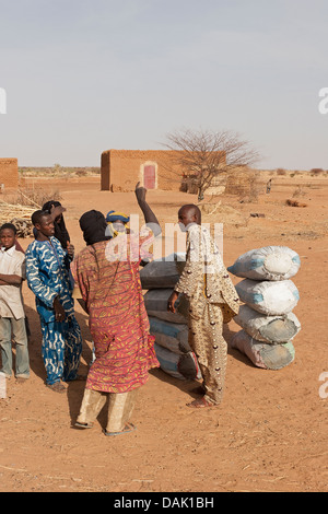 L'homme malien et le troc d'acheter des sacs de charbon de bois dans village sur la route de règlement à Gao au Mali l'Afrique de l'Ouest vente Banque D'Images