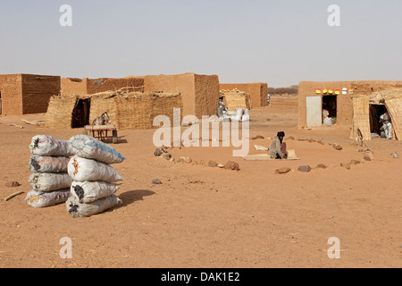 L'établissement village malien sur route à Gao avec le charbon de bois pour la vente et de cercle de pierres comme zone de prière de la mosquée, Mali, Afrique de l'Ouest Banque D'Images