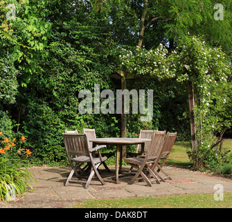 English Retour Jardin patio avec table et chaises et rose couverte arch Banque D'Images