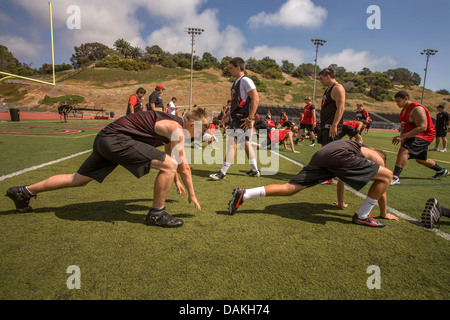 Les athlètes de l'école secondaire assouplir avec des exercices de flexibilité car ils commencent la pratique de football de printemps à San Clemente, CA. Banque D'Images