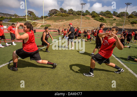 Les athlètes de l'école secondaire assouplir avec des exercices de flexibilité car ils commencent la pratique de football de printemps à San Clemente, CA. Banque D'Images