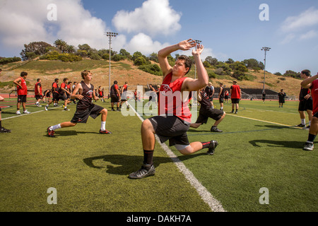 Les athlètes de l'école secondaire assouplir avec des exercices de flexibilité car ils commencent la pratique de football de printemps à San Clemente, CA. Banque D'Images