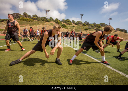 Les athlètes de l'école secondaire assouplir avec des exercices de flexibilité car ils commencent la pratique de football de printemps à San Clemente, CA. Banque D'Images