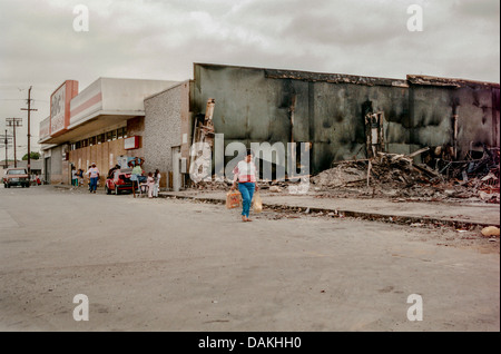 Les habitants hispaniques passer devant les ruines d'un incendie endommagé shop dans le centre Sud de Los Angeles après l'émeute de 1992 course Rodney King. Banque D'Images