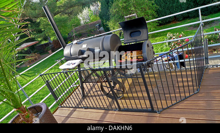 Grill plein de viande et charcuterie et entouré d'une clôture de protection des enfants sur une véranda Banque D'Images