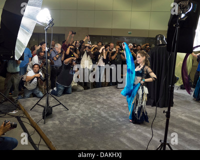 Sous l'éclairage de studio, les photographes amateurs foule photographier un modèle pendant une séance de photo à un salon photographique. Banque D'Images