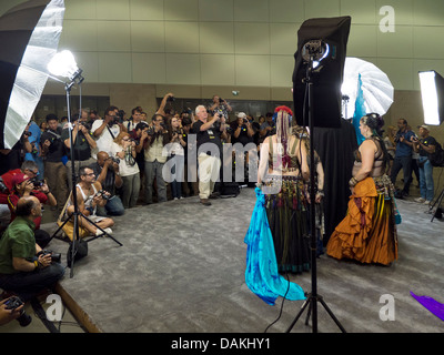 Sous l'éclairage de studio, les photographes amateurs foule photographie modèles pendant une séance de photo à un salon photographique. Banque D'Images