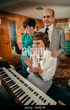 Un mari et sa femme sont rejoints par leur fille adulte dans une soirée de chansons à l'orgue à la maison familiale de Riverside, CA. Banque D'Images