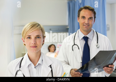 Doctors standing in hospital room Banque D'Images