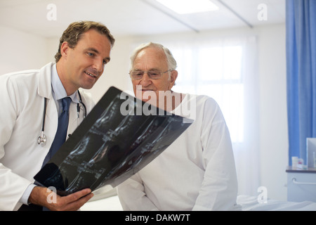 Médecin et patient examining x-rays in hospital room Banque D'Images