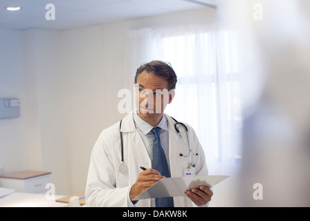 Doctor writing on clipboard in hospital Banque D'Images