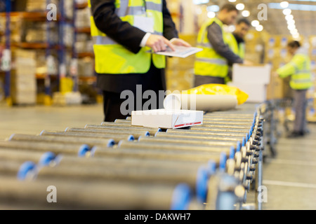 Les paquets de contrôle des travailleurs sur la courroie du convoyeur dans l'entrepôt Banque D'Images