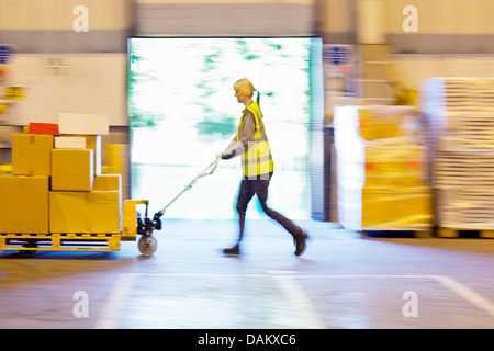 Blurred view of worker carting boxes in warehouse Banque D'Images