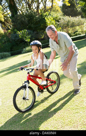 Older Man teaching petite-fille à circuler à bicyclette Banque D'Images