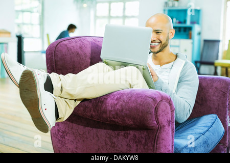 Man using laptop in armchair Banque D'Images