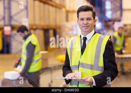 Businessman holding clipboard in warehouse Banque D'Images