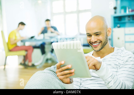 Man using tablet computer in living room Banque D'Images