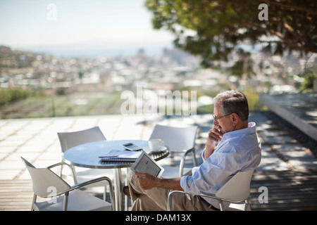 Older Man using tablet computer outdoors Banque D'Images