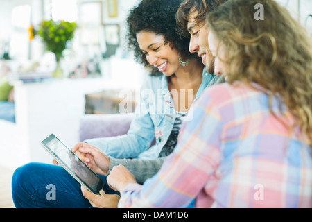 Friends using tablet computer on sofa Banque D'Images