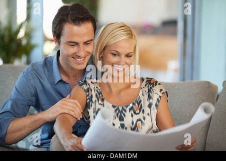 Couple examining blueprints ensemble sur canapé Banque D'Images