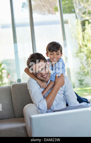 Père et fils à l'aide de l'ordinateur portable sur canapé Banque D'Images