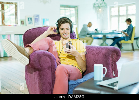 Man listening to headphones in armchair Banque D'Images