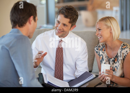 Financial Advisor talking to couple on sofa Banque D'Images